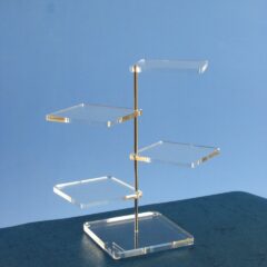 Présentoir en plexiglass à plusieurs niveaux avec plateaux carrés transparents fixés sur une tige métallique centrale, utilisé pour exposer médailles, objets ou bijoux.
