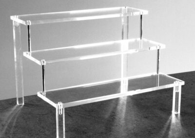 Étagère de présentation professionnelle en plexiglass transparent, modèle cascade quatre niveaux, conçue pour la mise en valeur d’objets en vitrine et en exposition.